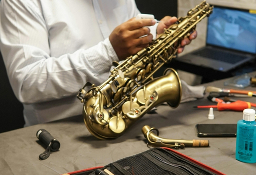 adjusting-saxophone-pads-03 Professional repairer servicing a saxaphone