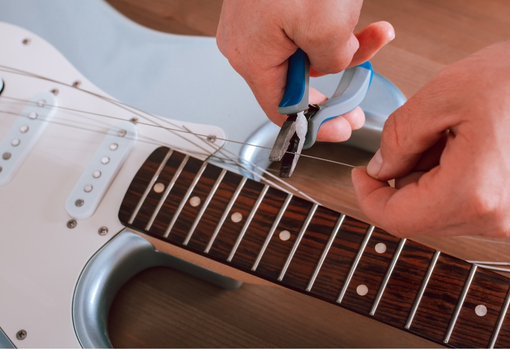 restringing-guitar-04 Professional repairer restringing a guitar