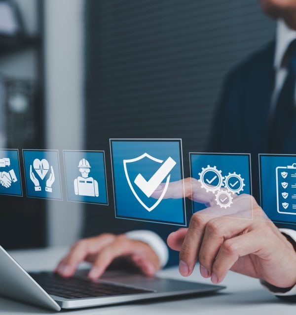 Work Safety and Compliance Concept. Businessman using laptop with icons safety, compliance, quality control, and risk management, representing workplace safety, regulations, and operational standards.